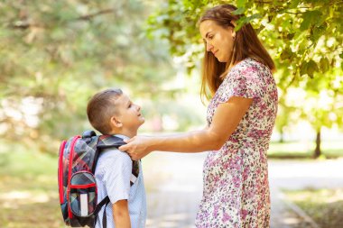 Back to school. Mother saying goodbye to her son as he leave for School. Schoolboy is ready go to school. First day at school.