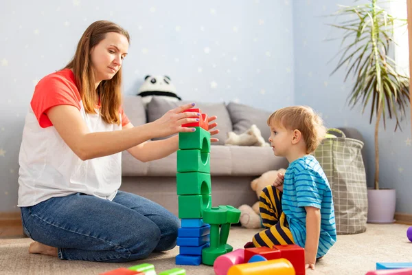 Happy loving family plays with plastic blocks and have fun. Mother and her baby son play together.