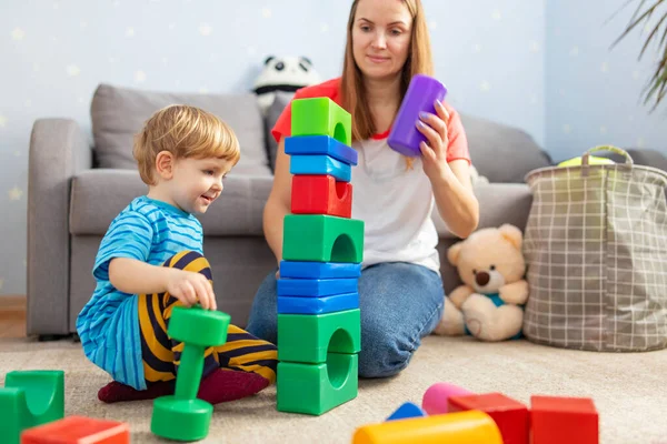 Happy loving family plays with plastic blocks and have fun. Mother and her baby son play together.