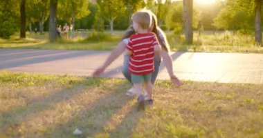 Mom hugs her little son takes him in her arms and together spin in park at sunset. Little boy hugs his mother in the park. Happy family, mother loves her child