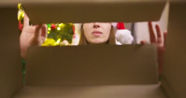 Schöne Junge Frau Mit Weihnachtsmütze Öffnet Weihnachtsgeschenkschachtel Mit Aufgeregtem Überraschtem — Stockvideo