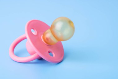 Orthodontic pacifier on a blue background. Pink baby pacifier on a blue background, space for text.