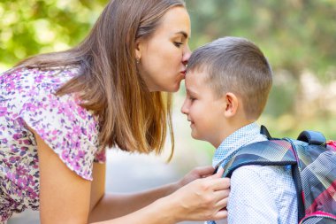 Back to school. Mother saying goodbye to her son as he leave for School. Schoolboy is ready go to school. First day at school.