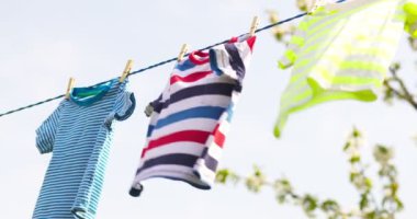 Clean clothes on rope outdoors on laundry day. Colorful t-shirts hanging on a laundry line against blue sky