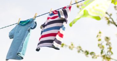 Clean clothes on rope outdoors on laundry day. Colorful t-shirts hanging on a laundry line against blue sky