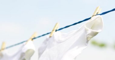 Beyaz bebek kıyafetleri bahar günü açık havada sallanıyor.