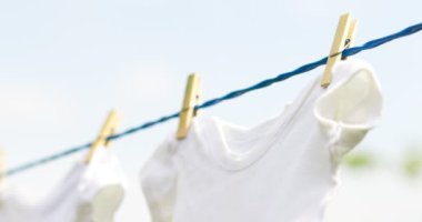 Beyaz bebek kıyafetleri bahar günü açık havada sallanıyor.