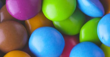 Yuvarlak renkli çikolata şekerlemeleri yavaş çekimde, Dragee. Döndürme ve düşme çok renkli çikolata şekerlemeleri