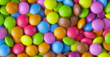 Yuvarlak renkli çikolata şekerlemeleri yavaş çekimde, Dragee. Döndürme ve düşme çok renkli çikolata şekerlemeleri