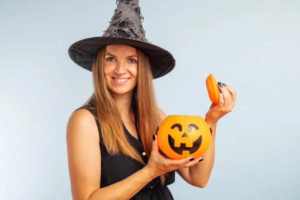 Happy Halloween! Happy young woman in halloween witch costume with pumpkin basket jack-o-lantern.