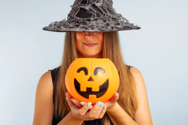 Happy Halloween! Happy young woman in halloween witch costume with pumpkin basket jack-o-lantern.