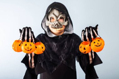 Happy Halloween! Cute little boy in a costume with many pumpkin baskets jack-o-lantern.