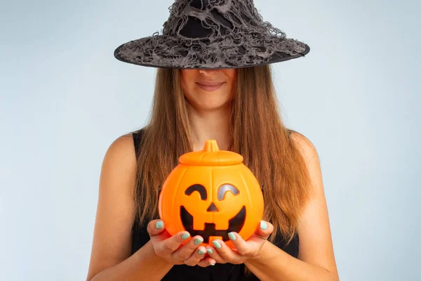 Happy Halloween. Happy young woman in halloween witch costume with pumpkin basket jack-o-lantern.