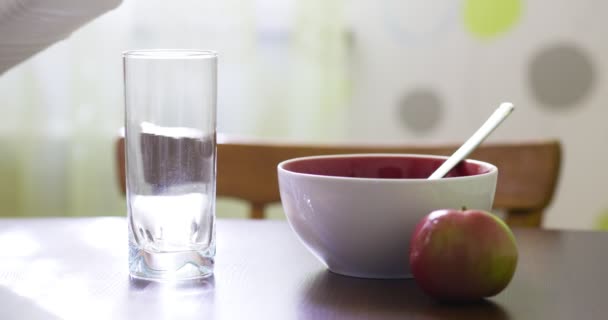 木製のテーブルの上に新鮮な牛乳を注ぎます 午前中は健康的な朝食 ボウルとミルクのグラスでフレーク — ストック動画