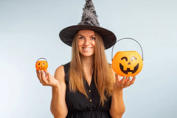 Happy Halloween. Happy young woman in halloween witch costume with two pumpkin baskets jack-o-lantern.