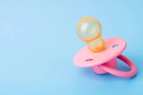 Orthodontic pacifier on a blue background. Pink baby pacifier on a blue background, space for text.