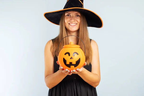 Happy Halloween. Happy young woman in halloween witch costume with pumpkin basket jack-o-lantern.