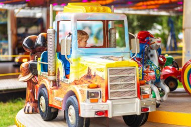 Küçük çocuk lunaparktaki atlıkarıncada eğleniyor..