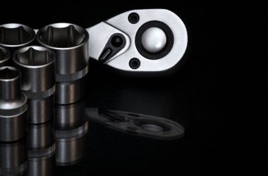 - İngiliz anahtarı. Parlak siyah yüzeyde paslanmaz çelik uğursuzluk yuvaları. Araba tamiri için evrensel profesyonel bir araç. Düşük tuşlu fotoğraf.