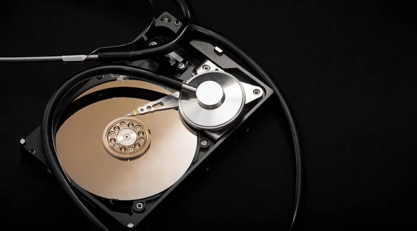 Internal parts of the hard drive. HDD. Computer memory. Modern technologies. Computer repair. Data storage concept. Black background. A stethoscope near the hard drive. Diagnostics concept. Recover lost data.
