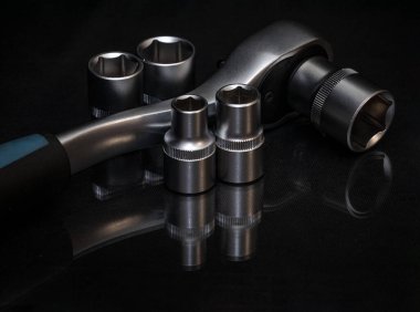 - İngiliz anahtarı. Parlak siyah yüzeyde paslanmaz çelik uğursuzluk yuvaları. Araba tamiri için evrensel profesyonel bir araç. Düşük tuşlu fotoğraf.