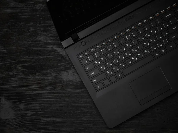 Gray laptop on a black wooden surface. Distance learning concept in quarantine. Modern freelance. Workplace. Distance communication. Low key photo.