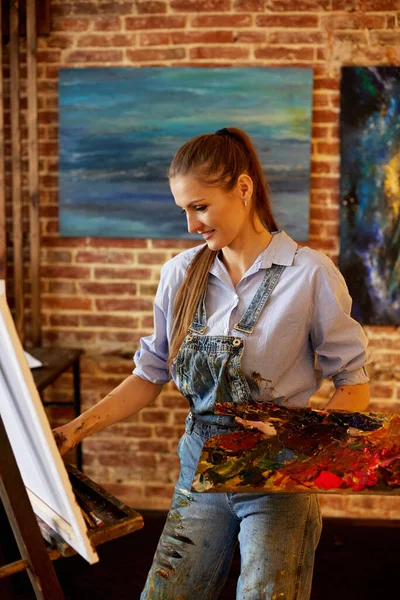 Yağlı boya tabloları ve palet bıçağıyla tuvale resim yapan genç ve güzel bir kadın sanatçı. Ressam sanat stüdyosunda sanat eseri yaratıyor. Rahatlama, rahatlama, hobi, stres yönetimi