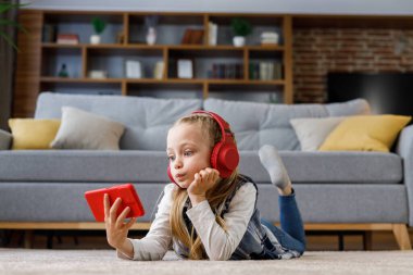 Evdeki halının üzerinde kırmızı kulaklık takan küçük kız şaşırdı. Akıllı telefon tutan, çizgi film izleyen, mesajlaşan, internette ve sosyal medyada gezinen, oyun oynayan tatlı kız..