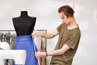 Portrait of a young fashion designer on the background of a mannequin and a sewing machine.