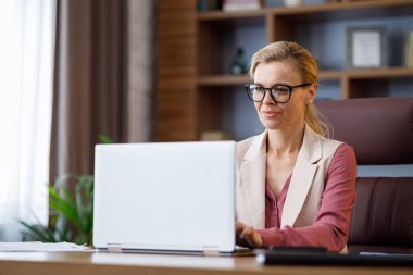 Portrait of beautiful businesswoman working with laptop at office. Texting messages, browsing internet, studying online, remote working. Business concept. Portrait of modern successful female leader.