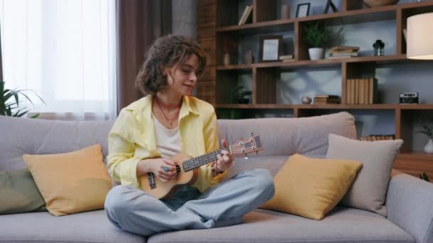 Beautiful Hipster Girl Yellow Shirt Plays Sings Ukulele Sofa Apartment — Vídeos de Stock