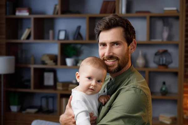 Close-up portrait of a father with a baby in his arms. Dad loves his little daughter, gently kisses. Father is on maternity leave. Paternity Leave. Paternal love.