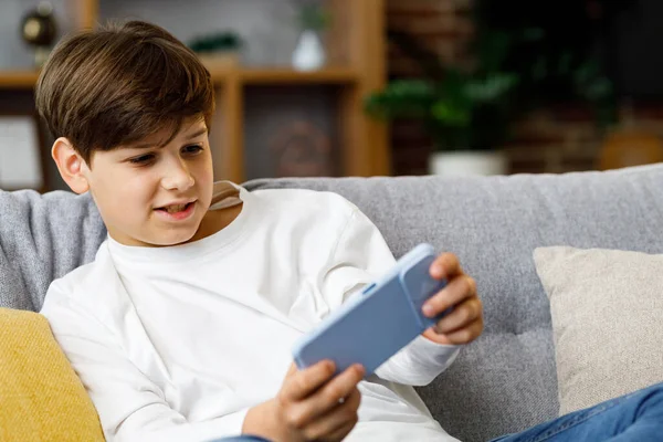Cheerful Young Boy Playing Video Game Smartphone Sitting Sofa Home —  Fotos de Stock