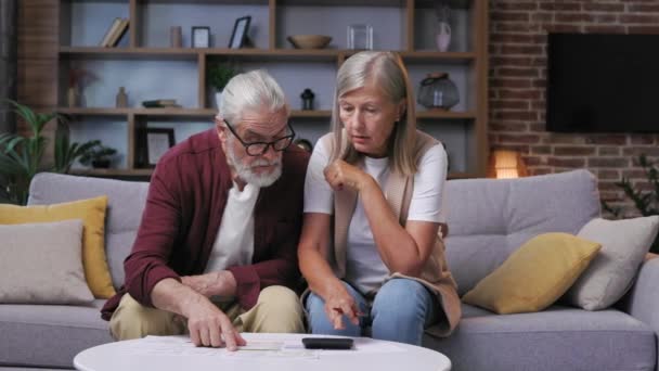 一对头发灰白的退休夫妇担心在计算器上计算公用事业费 养恤金领取者的大笔费用 能源和天然气费用 人口的能源危机 — 图库视频影像