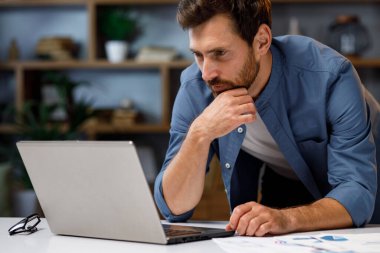 Şık bir ev ofisinde dizüstü bilgisayarın arkasında çalışan yakışıklı bir iş adamı. Uzaktan kumandalı iş. Başarılı bir serbest çalışanın portresi