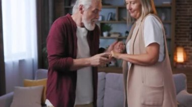 Yaşlı mutlu çift evde dans ediyor. Gri saçlı karı koca dans ediyor. Mutlu yaşlıların ilişkileri işte. Orta yaşlı büyükanne ve büyükbaba evde birlikte dinleniyorlar..