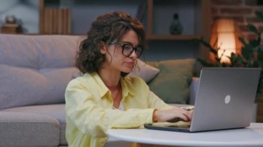 Yorgun genç kıvırcık öğrenci online çalışmayı durdurur, gözlüğünü çıkarır, burnunun köprüsüne masaj yapar. Bitkin, bitkin. Bilgisayarda aşırı çalışma, yorgunluk, göz yorgunluğu..