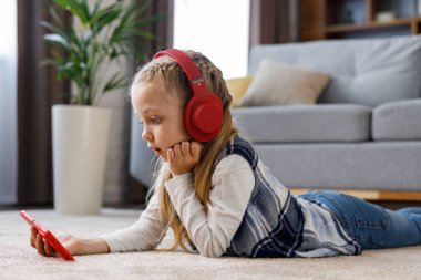 Evdeki halının üzerinde kırmızı kulaklık takan küçük kız şaşırdı. Akıllı telefon tutan, çizgi film izleyen, mesajlaşan, internette ve sosyal medyada gezinen, oyun oynayan tatlı kız..