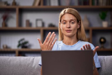 Kadın uzaktan çalışırken video bağlantısı ile iletişim kuruyor. Kendine güvenen, serbest çalışan, konuşan, el kol hareketi yapan, online bir konferans düzenleyen ve webcam 'e bakan bir kadın. İçişleri Bakanlığı