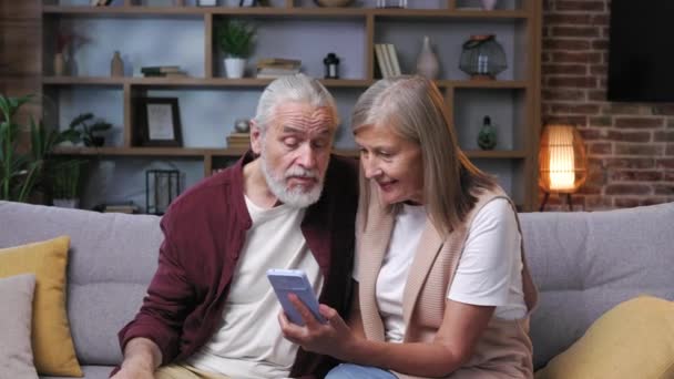 成熟快乐的夫妇使用智能手机 一对白发苍苍的夫妻在电话里看到了这个消息 是的养恤金领取者快乐年长的祖父母学习使用现代技术小玩意的概念 — 图库视频影像