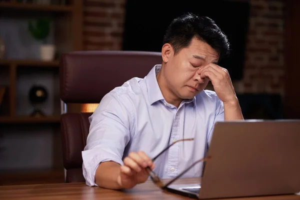 沮丧的亚洲人坐在办公室里 按摩鼻梁 防止眼部疲劳 屏幕后视力差 — 图库照片