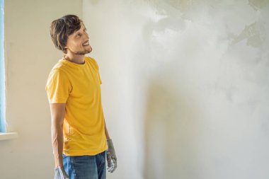 Sıvacı ev iyileştirme ustası macun bıçağıyla apartman duvarını doldurmaya çalışıyor.