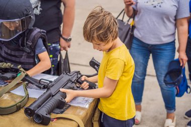 Küçük bir çocuk askeri teçhizat okuyor. Savaş yok.