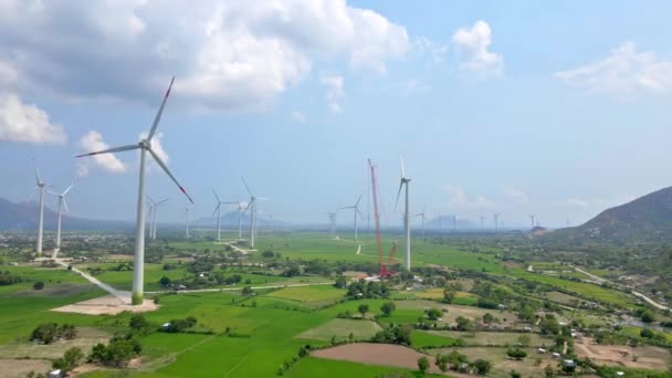 Tiro aéreo. Um grande verde arquivado com muitas usinas eólicas. Uma usina está em construção. Investimento em energia verde. Conceito de electricidade verde — Vídeo de Stock