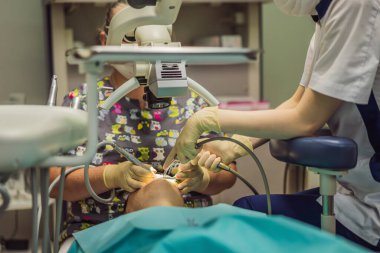 Mikroskopla diş tedavisi. Dişçileri muayene eden bir kadın. Dişçide randevum var. Yaşam tarzı, gerçek hayat.