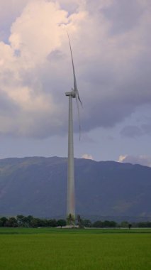 Dikey video. El kamerasıyla. Yeşil bir alanda rüzgar enerjili bir türbin. Yeşil enerjiye yatırım. Yeşil elektrik kavramı