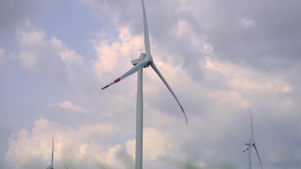 Handheld shot. A wind power turbine with a blue cloudy sky in the background. Investments in green energy. Green electricity concept — Stock Video