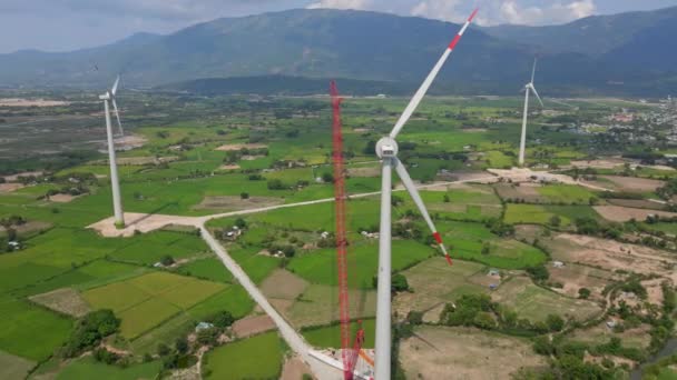 Aerial shot. A big green filed with lots of wind power plants. One power plant is under construction. Investment in green energy. Green electricity concept — Stock Video