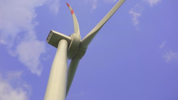 Een handschot. Een windturbine met een blauwe bewolkte lucht op de achtergrond. Investeringen in groene energie. Concept groene elektriciteit — Stockvideo