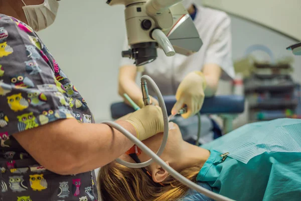 Tandheelkundige behandeling met een microscoop. Een vrouw die tanden laat onderzoeken bij tandartsen. Afspraak bij de tandarts. lifestyle, het echte leven — Stockfoto